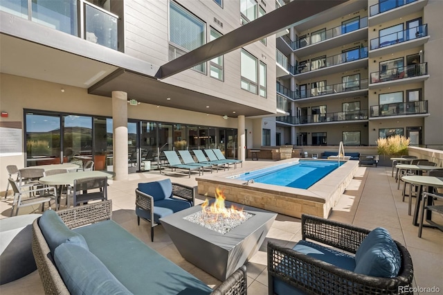 view of swimming pool featuring an outdoor living space with a fire pit and a patio