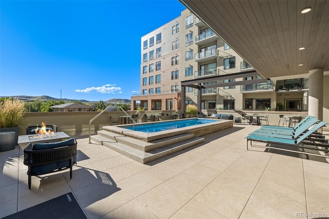 view of pool featuring a patio area, a fire pit, and a mountain view