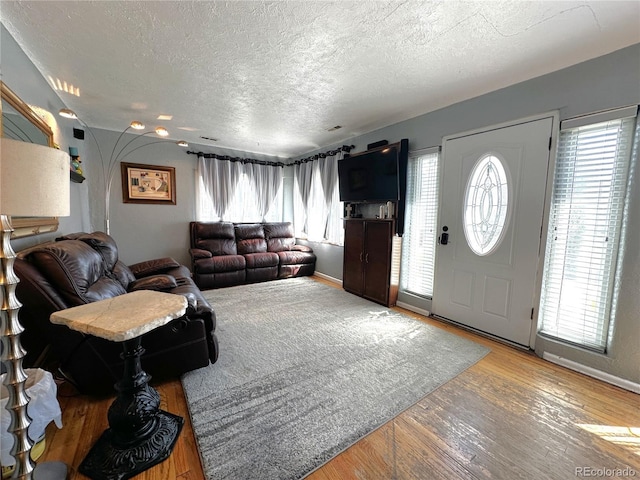 living room with baseboards, a textured ceiling, and wood finished floors