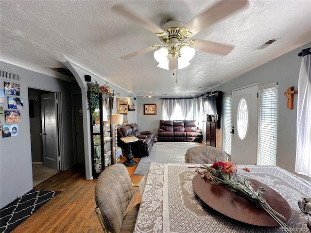 dining area featuring visible vents, a textured ceiling, ceiling fan, and wood finished floors