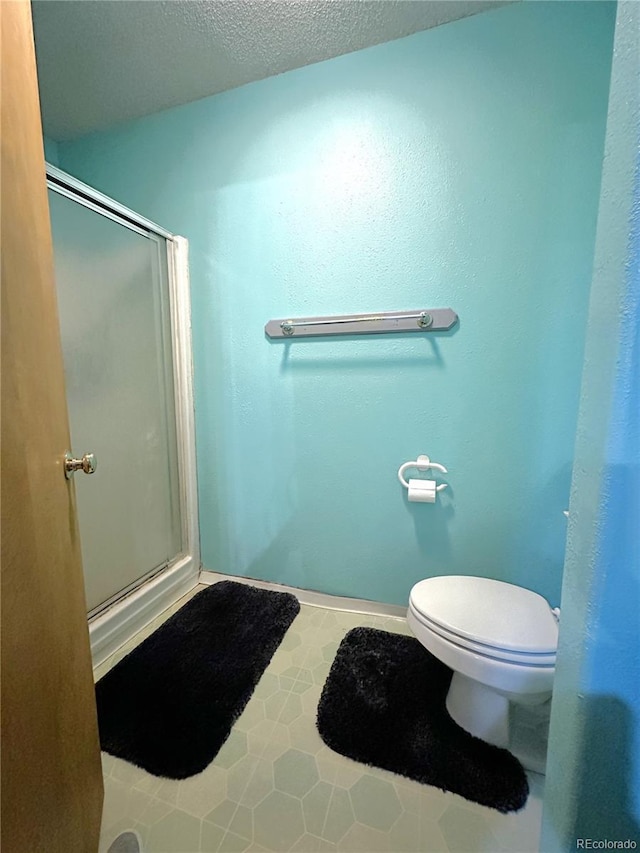 bathroom with tile patterned flooring, a shower stall, toilet, and a textured ceiling