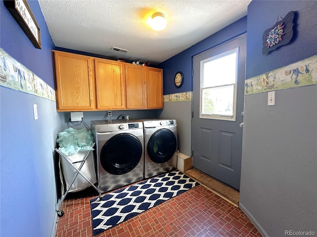 clothes washing area with washer and dryer, cabinet space, a textured ceiling, baseboards, and visible vents