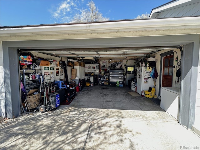 garage featuring freestanding refrigerator and concrete driveway