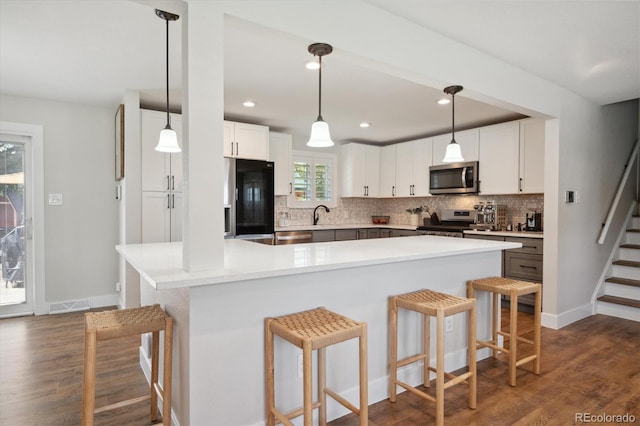 8242 E Briarwood Pl, Centennial, CO 80112 - kitchen featuring stainless steel appliances, dark wood-style floors, a breakfast bar, backsplash, and recessed lighting