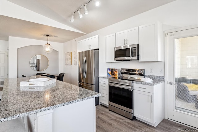 kitchen with lofted ceiling, white cabinetry, light stone counters, pendant lighting, and stainless steel appliances