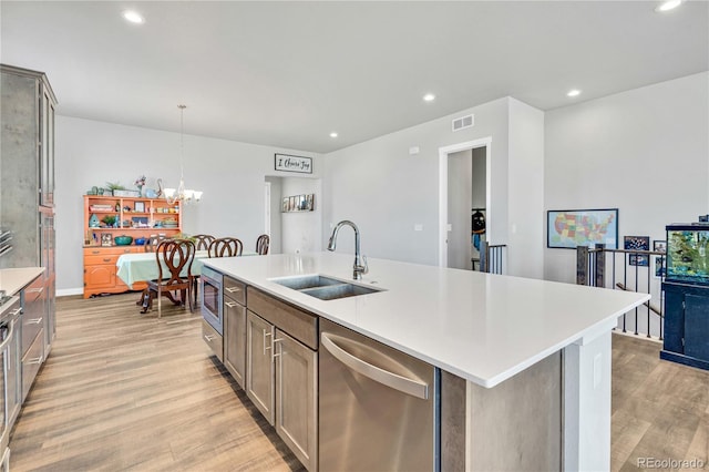 kitchen with stainless steel appliances, visible vents, a sink, light countertops, and light wood-type flooring
