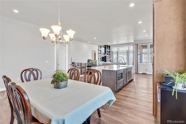 dining space featuring a chandelier, light wood-style flooring, baseboards, and recessed lighting