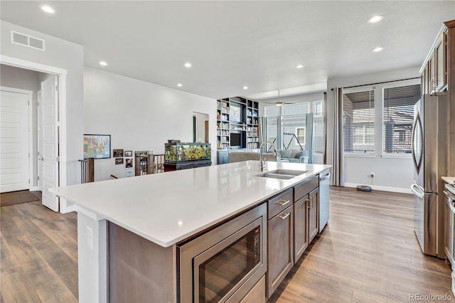 kitchen with a sink, wood finished floors, visible vents, and appliances with stainless steel finishes