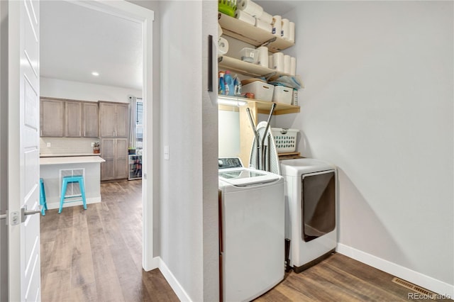 laundry room with separate washer and dryer, laundry area, wood finished floors, and baseboards