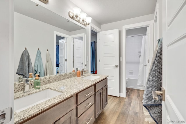 bathroom featuring baseboards, double vanity, a sink, and wood finished floors