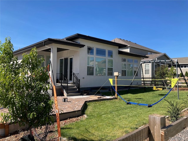 back of property with a yard, stucco siding, and fence