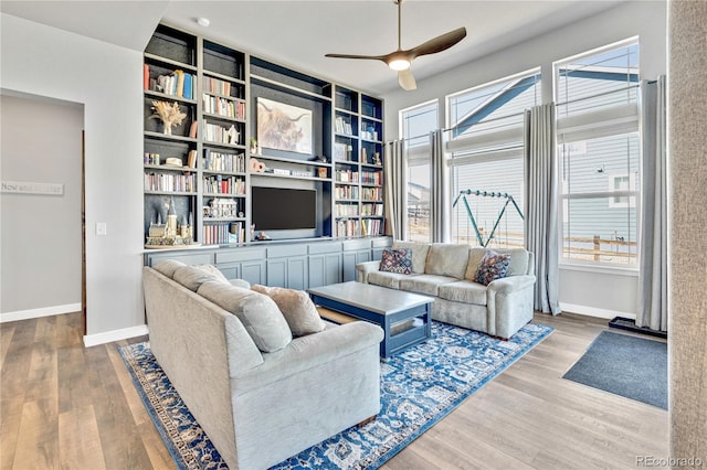 living area with baseboards, ceiling fan, built in features, and wood finished floors