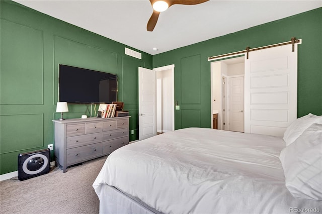 bedroom featuring carpet, visible vents, a barn door, a decorative wall, and ceiling fan