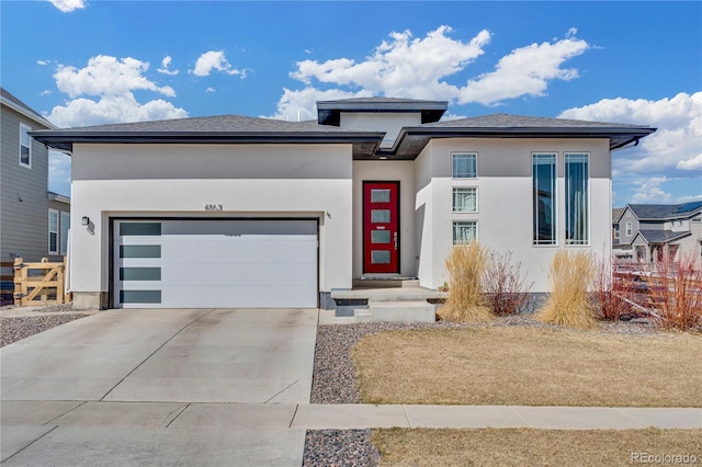 prairie-style house with an attached garage, stucco siding, and driveway