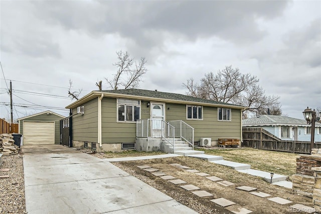 view of front facade featuring a detached garage, an outbuilding, concrete driveway, and fence