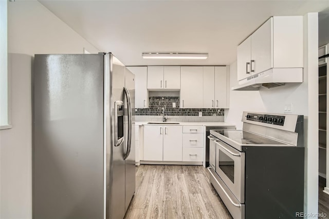 kitchen featuring under cabinet range hood, a sink, stainless steel appliances, white cabinets, and light wood finished floors