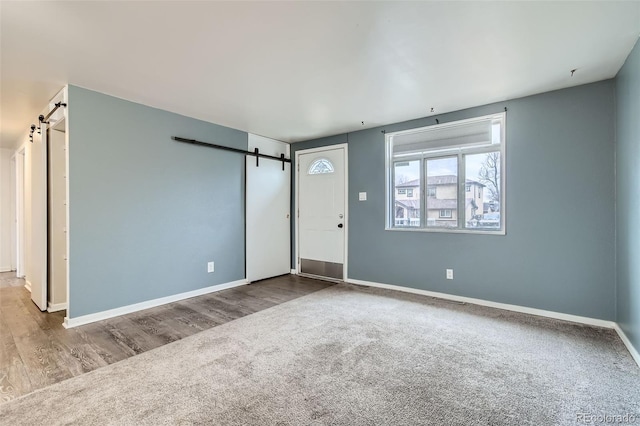 unfurnished living room with a barn door, visible vents, baseboards, and carpet floors