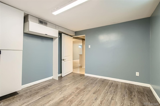 finished below grade area with visible vents, light wood-type flooring, and baseboards