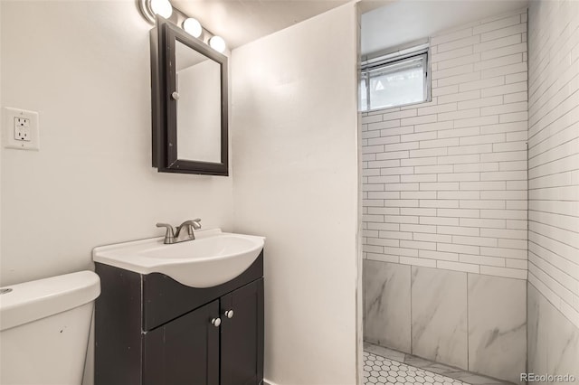 bathroom with toilet, vanity, and a tile shower