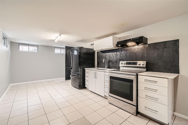 kitchen with stainless steel electric stove, light countertops, range hood, freestanding refrigerator, and a sink