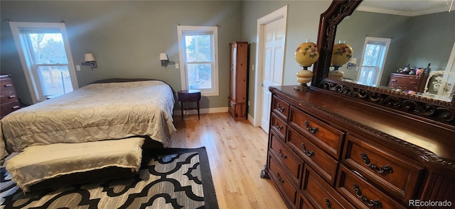 bedroom featuring light wood-type flooring, ornamental molding, and multiple windows