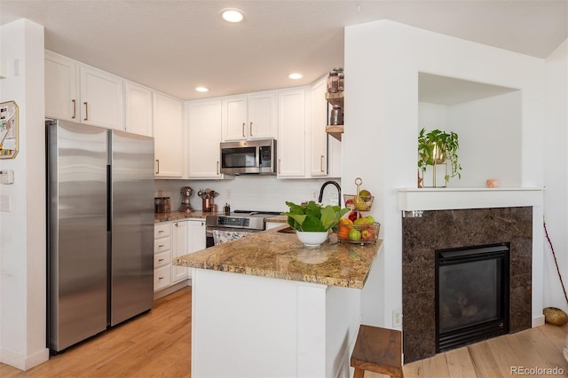 661 Snowberry St, Longmont, CO 80503 - kitchen with white cabinets, stainless steel appliances, a peninsula, and light wood-type flooring
