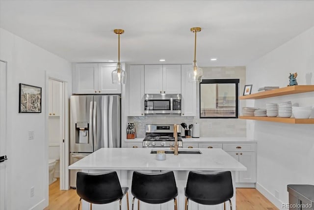 kitchen with decorative light fixtures, white cabinetry, a breakfast bar, and appliances with stainless steel finishes