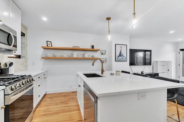 kitchen featuring sink, white cabinets, a breakfast bar area, hanging light fixtures, and appliances with stainless steel finishes