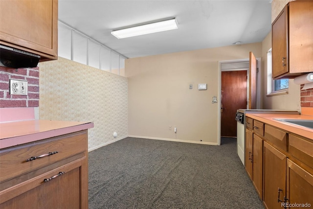 kitchen with brown cabinetry, dark colored carpet, and light countertops