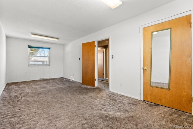 carpeted spare room featuring visible vents and a textured ceiling