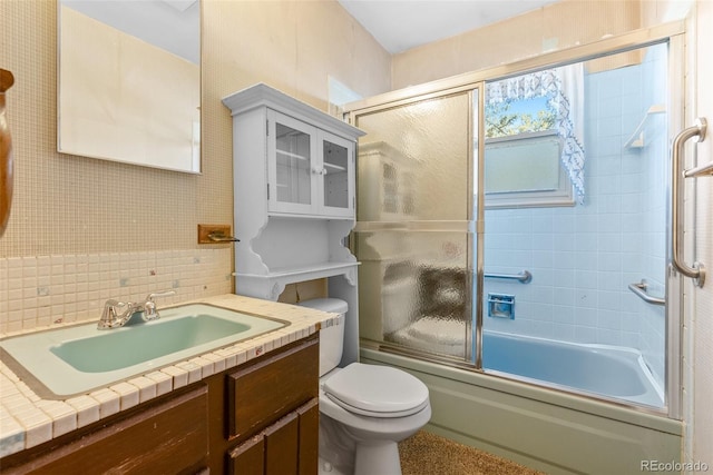 bathroom featuring decorative backsplash, combined bath / shower with glass door, vanity, and toilet