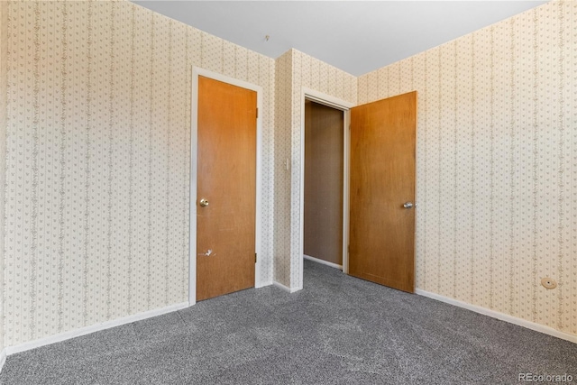 unfurnished bedroom with wallpapered walls, baseboards, and carpet flooring