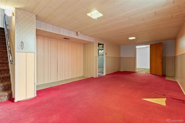 carpeted empty room with a wainscoted wall, stairway, and wood ceiling