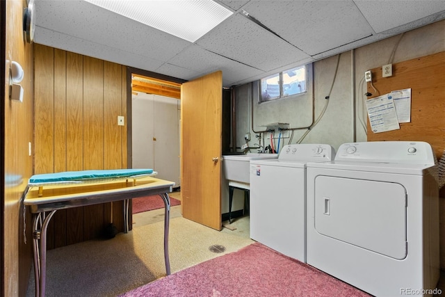 laundry area featuring carpet, washing machine and dryer, a sink, wooden walls, and laundry area