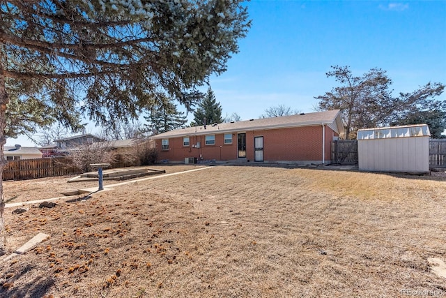 rear view of house with a storage shed, fence, an outdoor structure, and brick siding