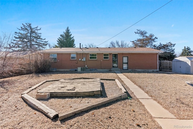 rear view of property featuring fence, an outdoor structure, central air condition unit, a shed, and brick siding