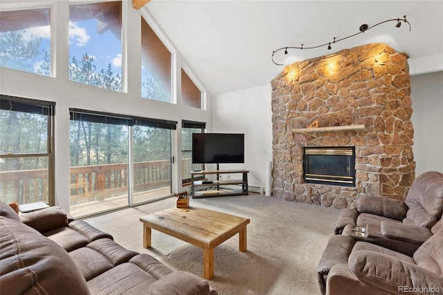 living room featuring a baseboard radiator, high vaulted ceiling, a stone fireplace, and carpet floors