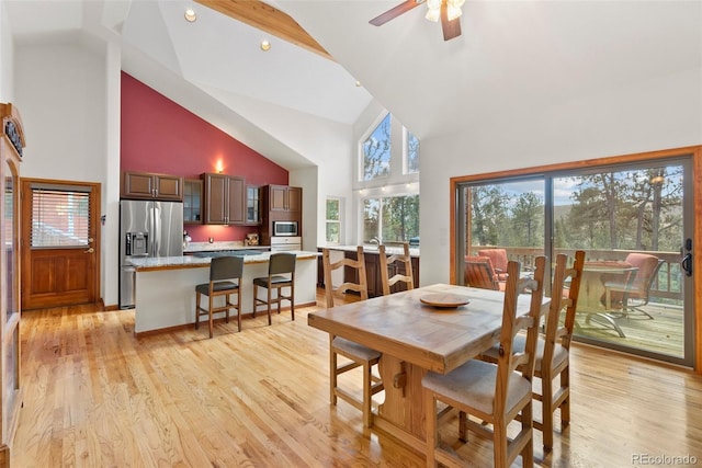 dining area with ceiling fan, high vaulted ceiling, and light hardwood / wood-style flooring