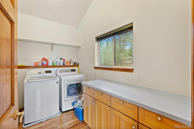 washroom with washer and dryer, cabinets, and light hardwood / wood-style flooring