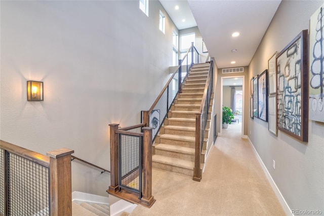 stairway featuring a wealth of natural light and carpet floors