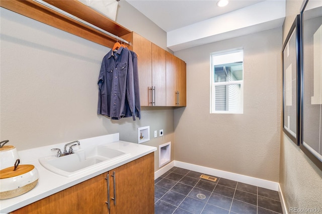 washroom with sink, cabinets, washer hookup, hookup for an electric dryer, and dark tile patterned flooring