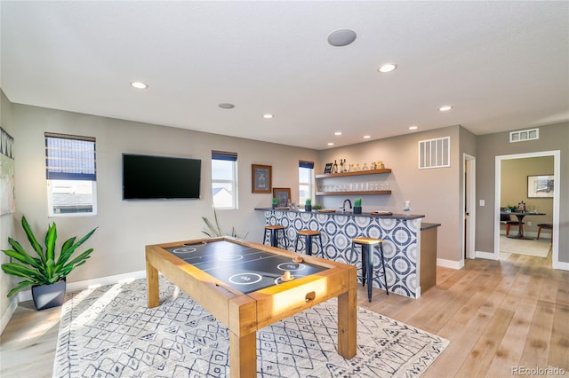 game room featuring indoor bar and light wood-type flooring