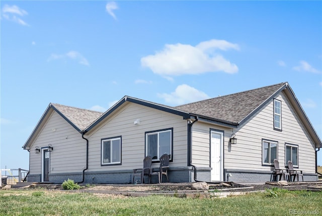 back of house with a yard and roof with shingles