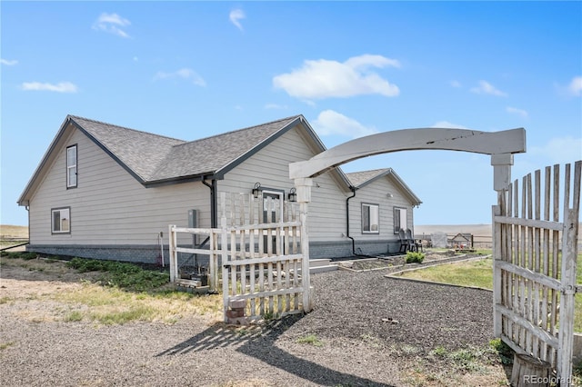 view of front of home featuring fence and roof with shingles