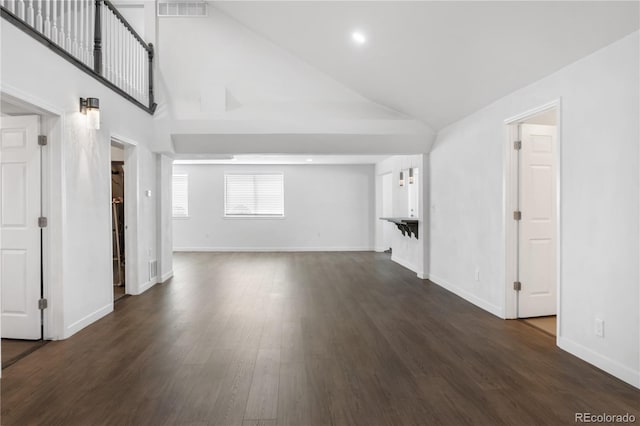 unfurnished living room with high vaulted ceiling, dark wood finished floors, visible vents, and baseboards