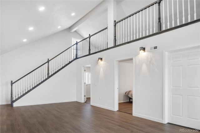 unfurnished living room with visible vents, wood finished floors, high vaulted ceiling, beamed ceiling, and baseboards