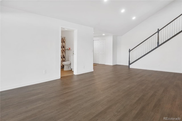 unfurnished living room with dark wood-style flooring, stairway, and baseboards