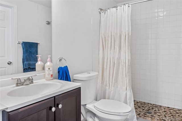 full bath with tiled shower, vanity, and toilet