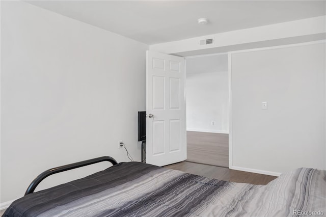 unfurnished bedroom with wood finished floors, visible vents, and baseboards