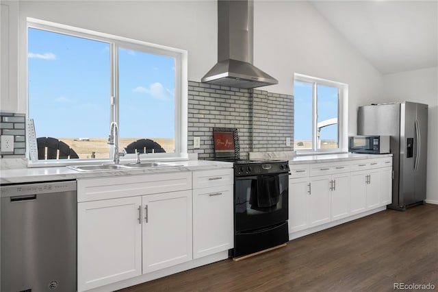 kitchen featuring dark wood finished floors, lofted ceiling, stainless steel appliances, wall chimney range hood, and a sink